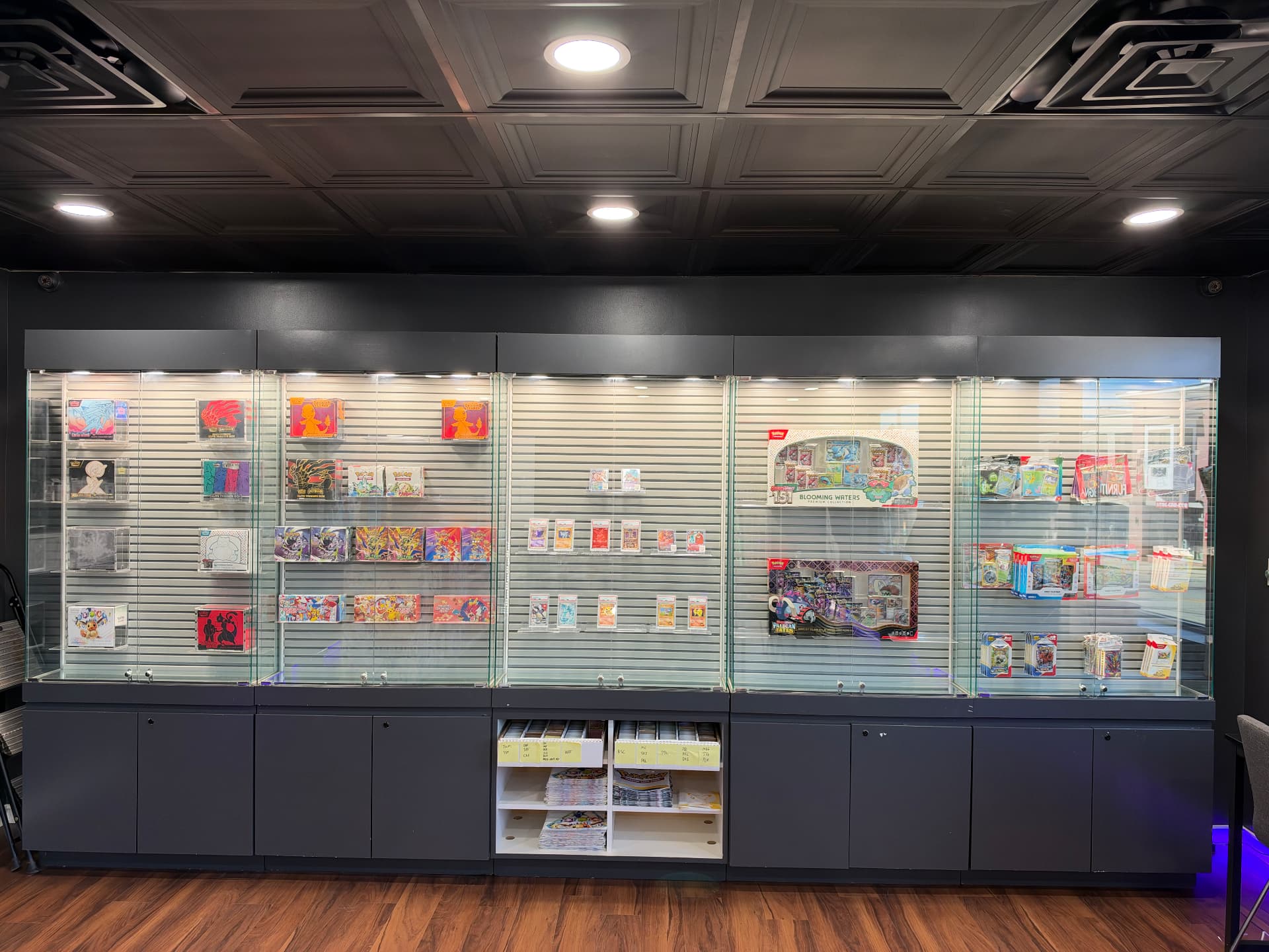 Lit glass display wall of sealed Pokémon products and graded cards at Trading Vaults